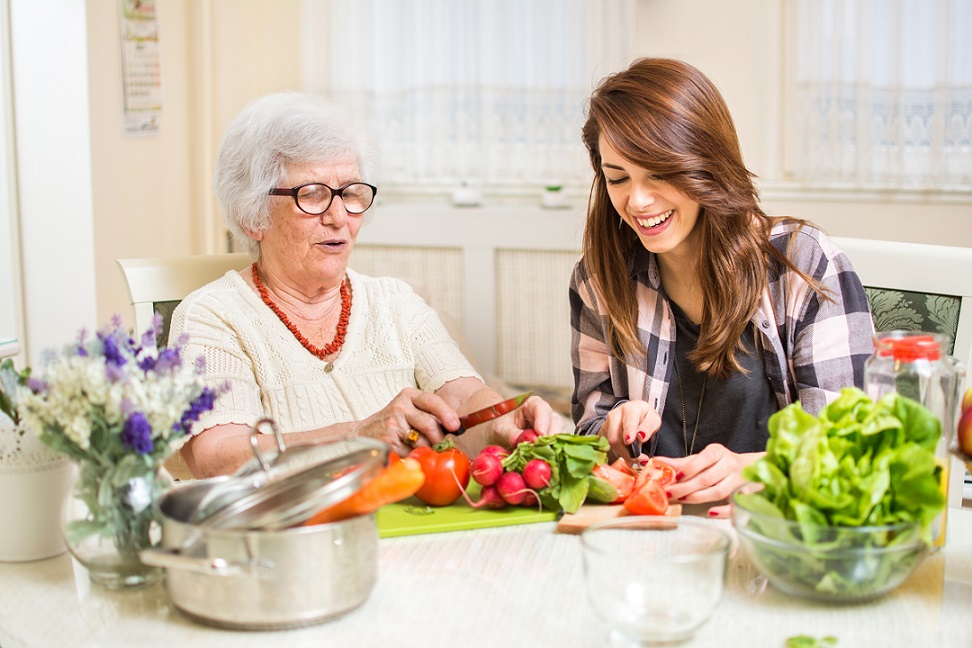 grandmother and granddaughter cutting vegetables for healthy food. Happy senior