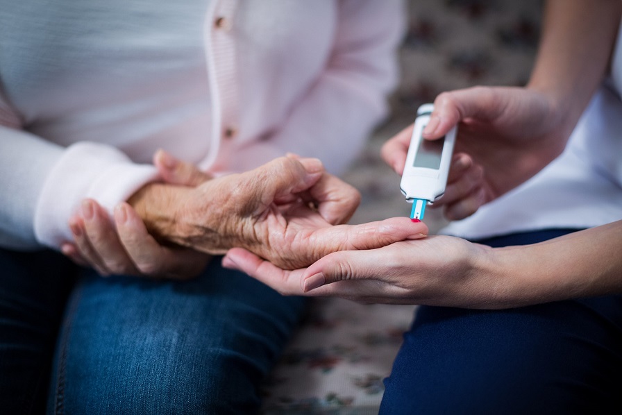Caregiver is testing a senior  fast blood sugar.