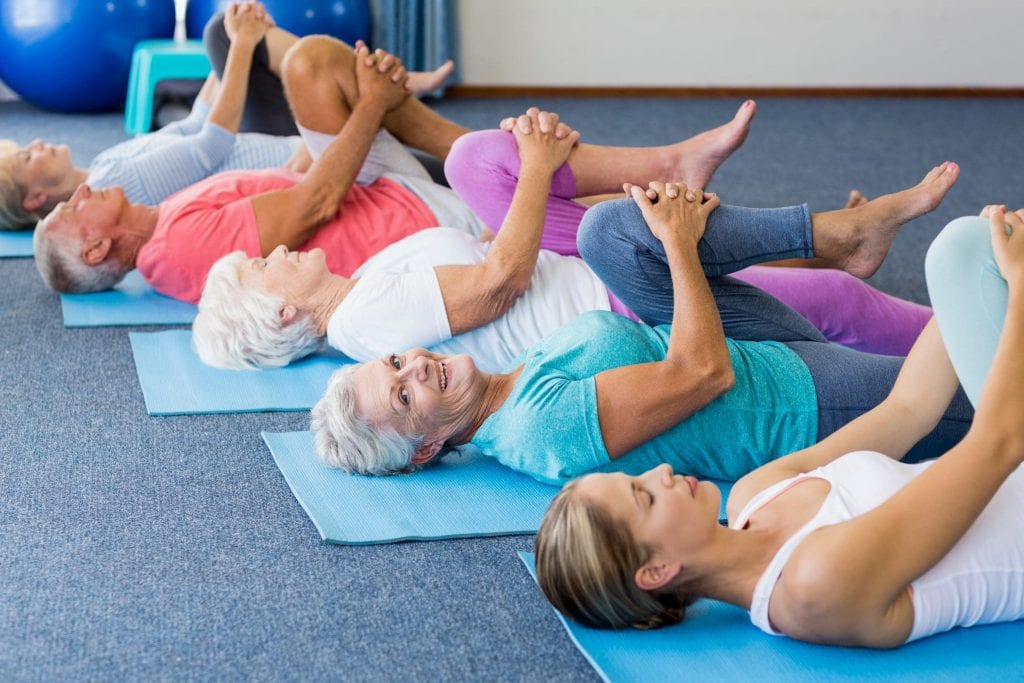 Seniors exercising yoga in a group. An old lady is smiling