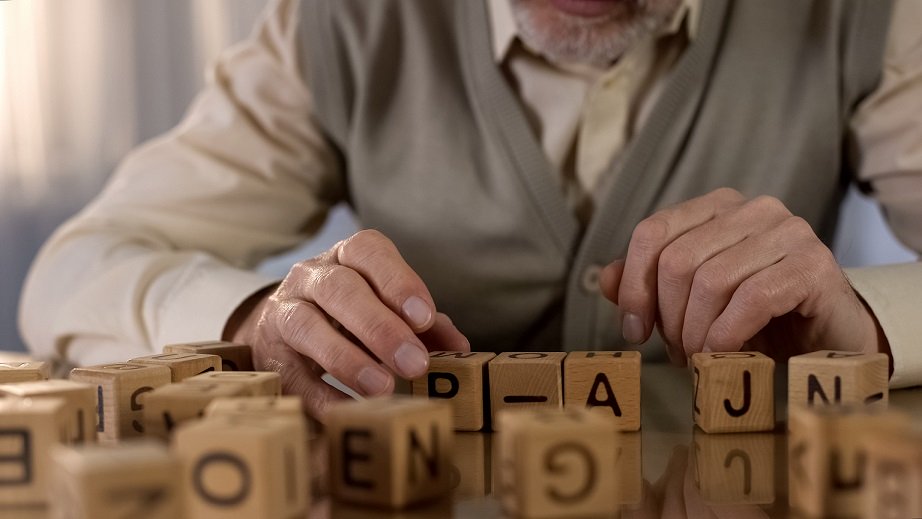 An old man is playing with alphabet blocks to prevent Alzheimer 