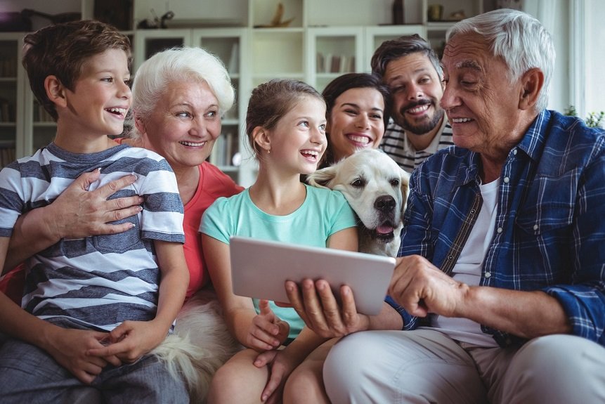 Grandparents happily playing with kids using their tablet.