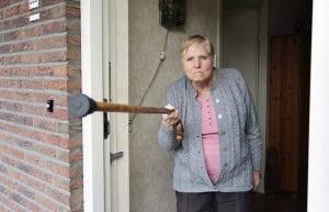 Elderly angry woman threatening with a cane in the doorway