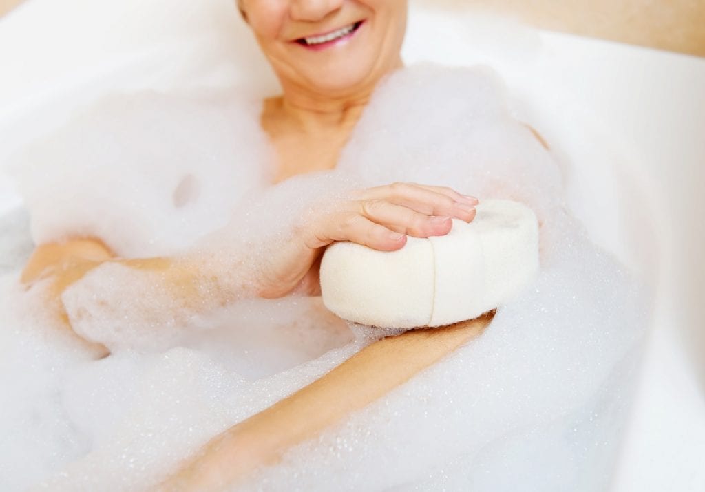 A senior woman is relaxing in a bath tub .