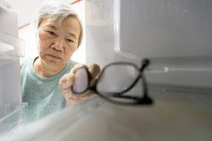 Asian elderly woman with memory impairment symptoms, forgets her glasses in the refrigerator