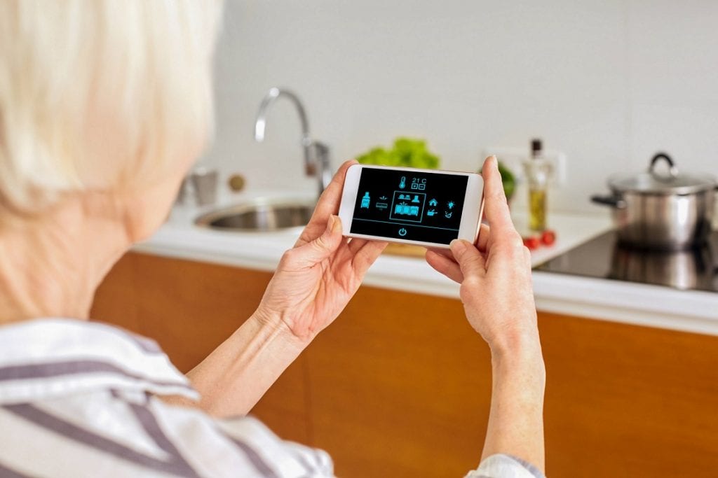 A senior woman is Checking her smart house on an application in her smartphone .