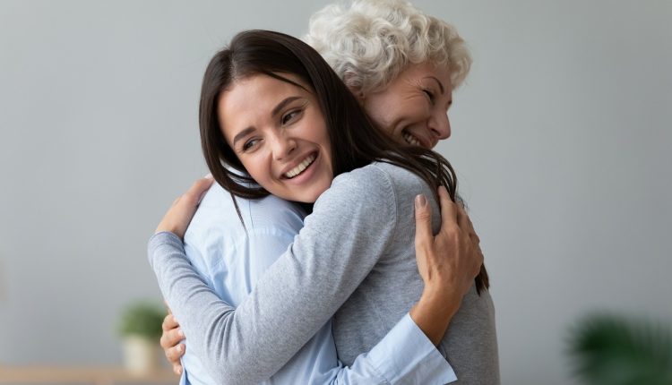 Happy young girl visiting embracing hugging grandmother and cuddling.