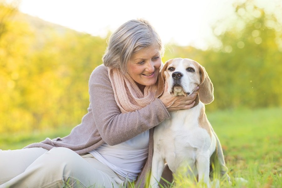 an elderly woman sitting by her pet