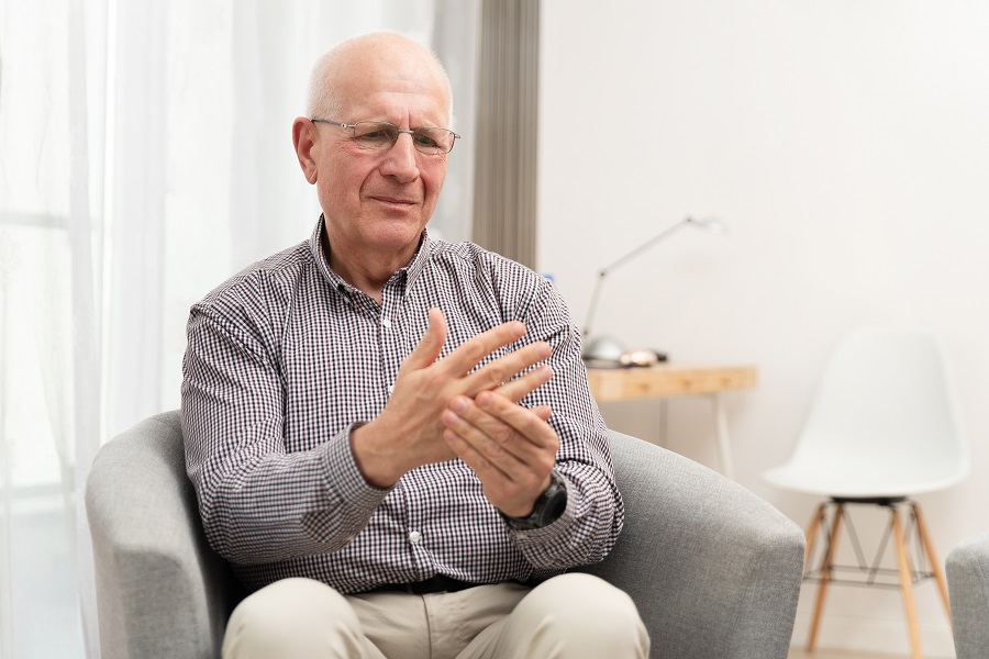 an elderly man giving himself a hand massage