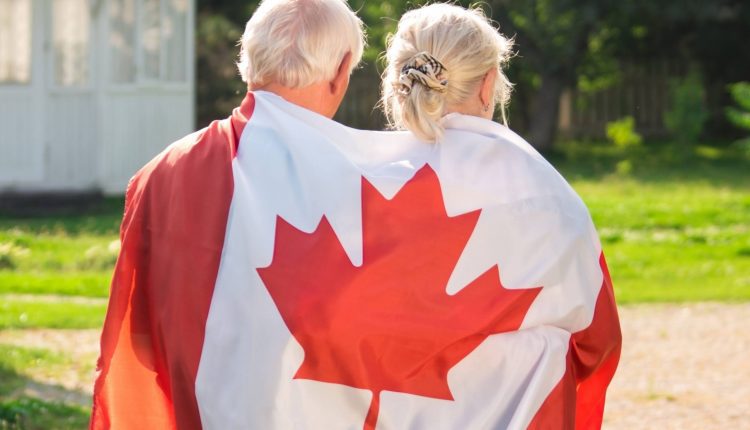 Two seniors walking with a the Canadian flag on their shoulders