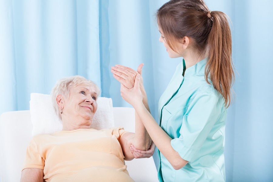 a senior woman receiving hand massage by her caregiver