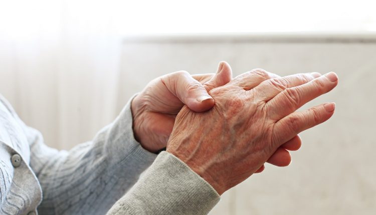 An elderly massaging his own hand