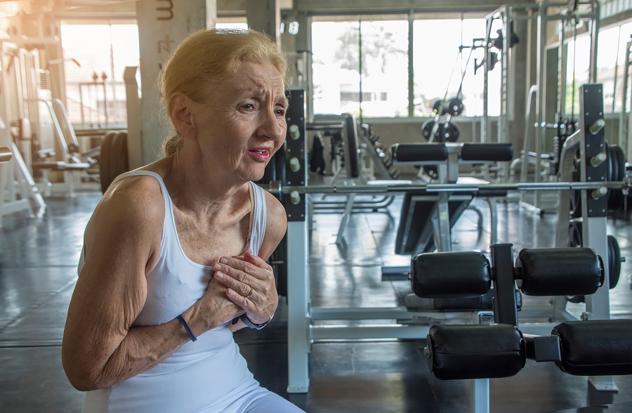 an elderly woman experiencing heart problem during exercising at the gym. dangers of heavy exercise