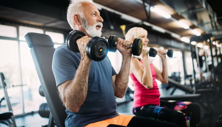 Two seniors working with dumbbells at the gym