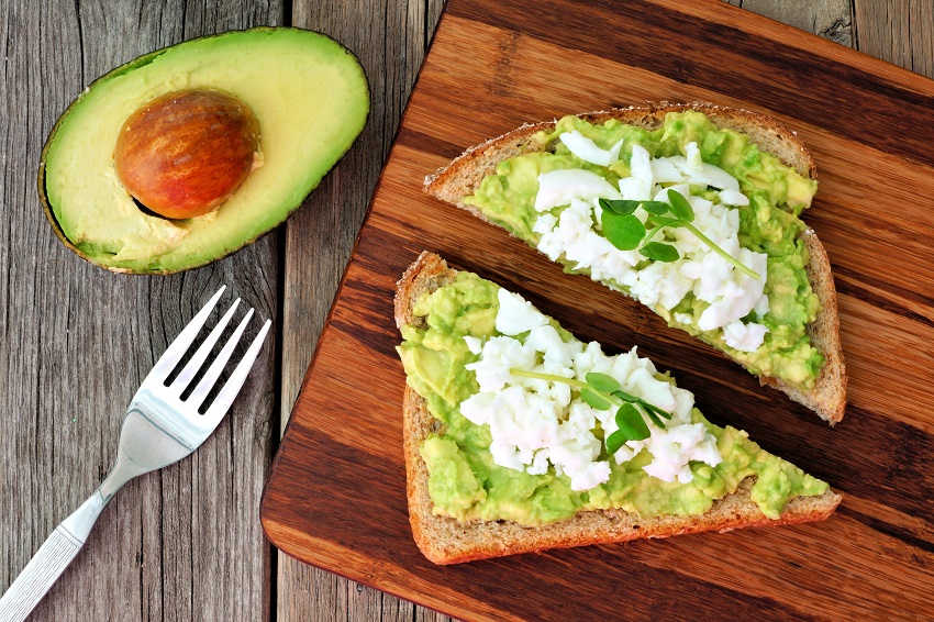 two slices of avocado toast topped with scrambled eggs