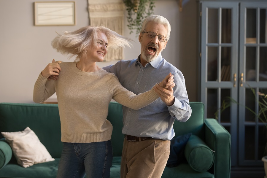 a senior couple are dancing at home