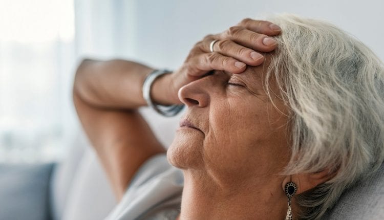 a tired senior woman sitting on sofa with closed eyes