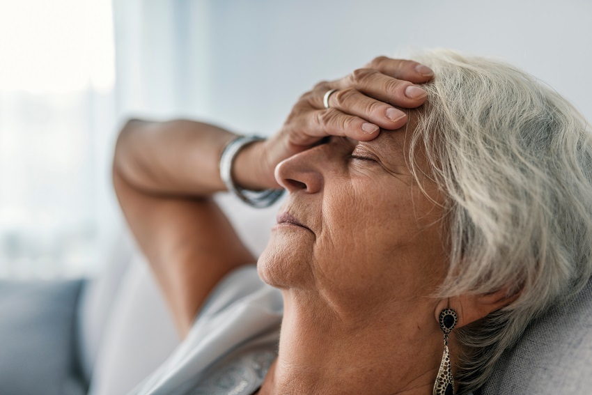 a tired senior woman sitting on sofa with closed eyes