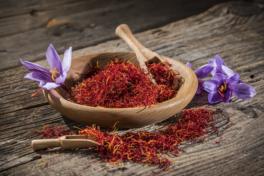 some saffron on a wooden table and a few saffron blooms