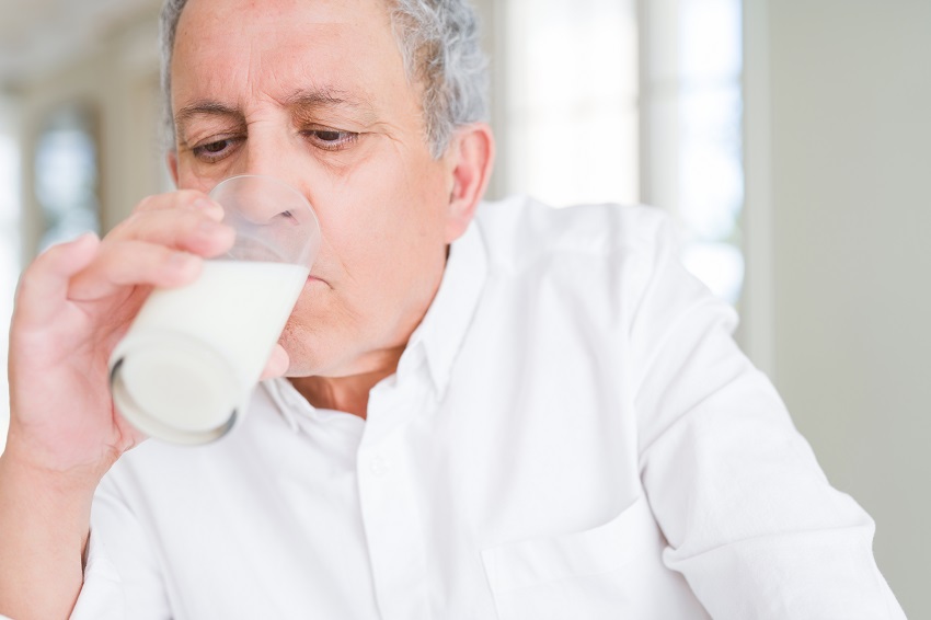a senior man drinking a glass of milk