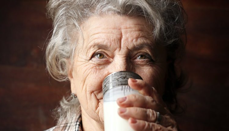 a senior woman drinking a glass of milk