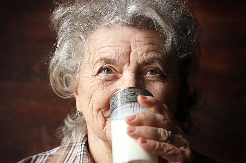 a senior woman drinking a glass of milk