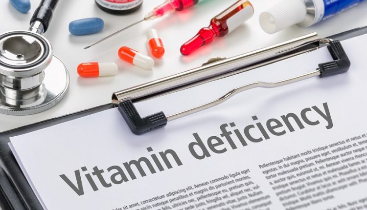 vitamin deficiency written on a piece of paper beside a few capsules and a syringe