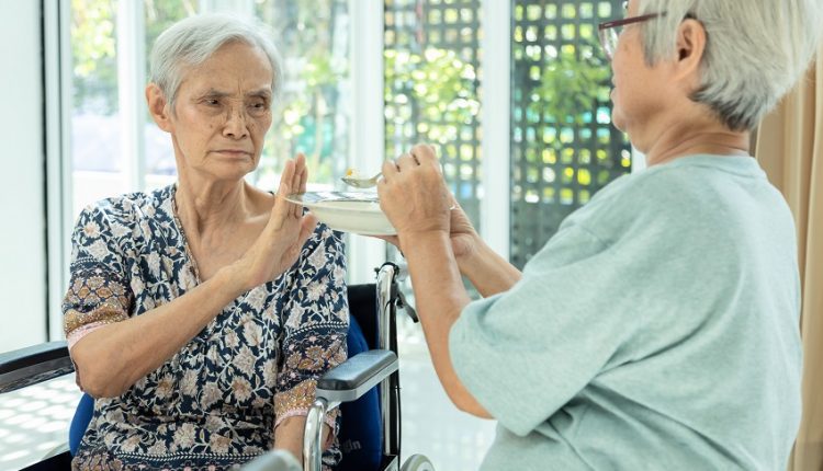 Unhappy Asian senior woman rejecting food due to anorexia