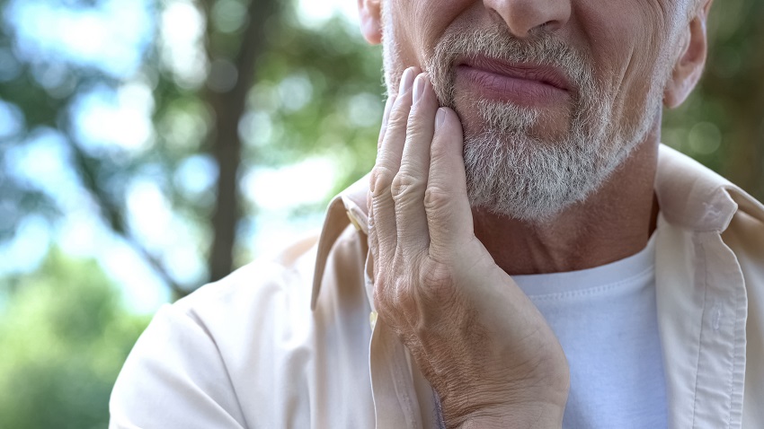 a senior man touching his face due to dental pain