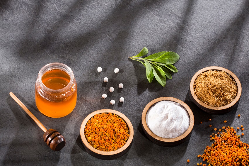 Several natural sweeteners in bowl on a black background