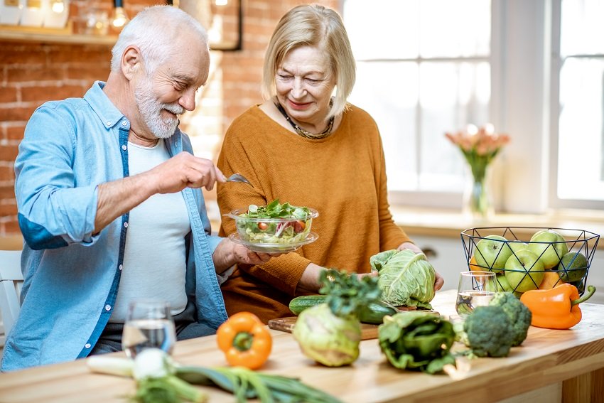A senior couple making food in the kitchen