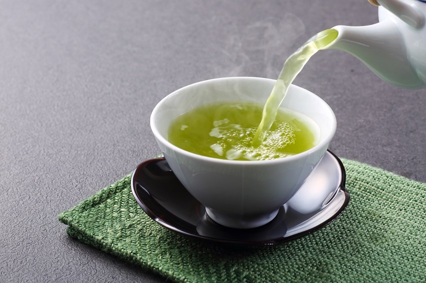 pouring green tea from a kettle into a cup