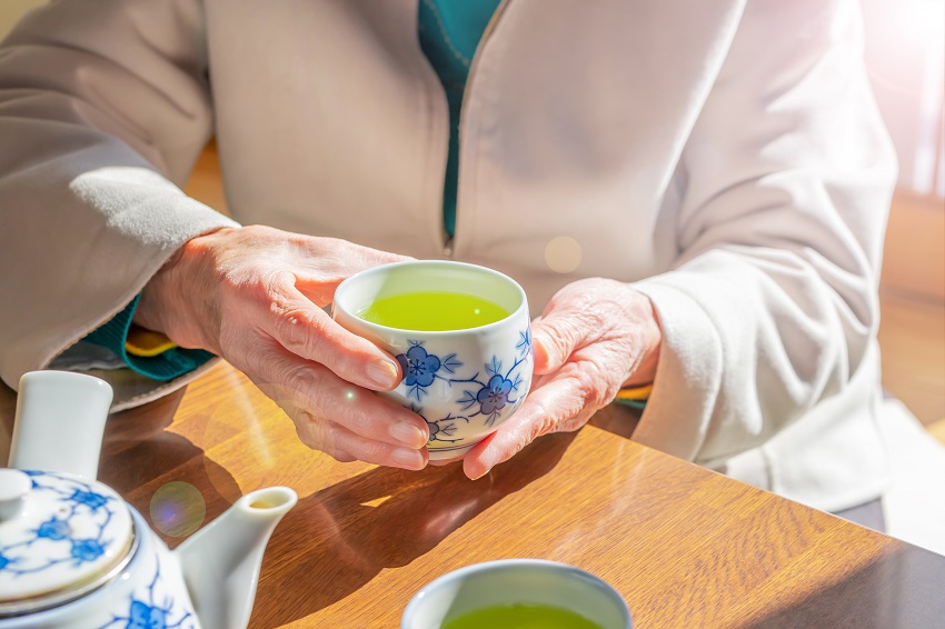 a senior woman holding a cup of green tea