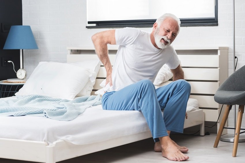 A senior sitting on bed having back pain