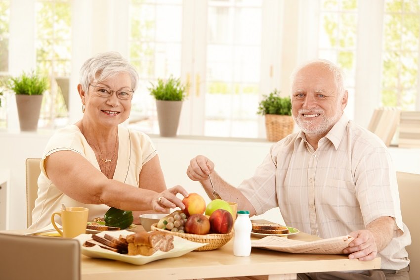 a senior couple eating fruits at the table