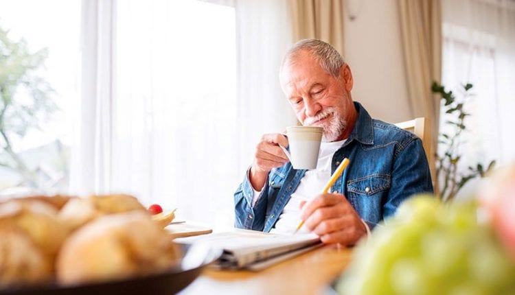 Senior man solving a crossword puzzle at the breakfast table