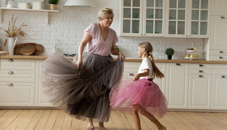 Happy energetic grandmother dancing with her granddaughter