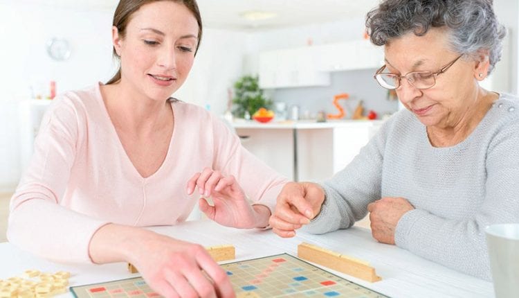 Senior woman playing scrabble with a young woman. games to play with dementia patients, games to play with the elderly with dementia, 