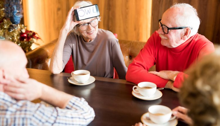 A Happy Group of seniors playing sticky head with a phone