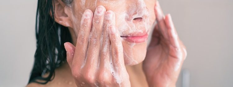 An older woman washing her face with soap