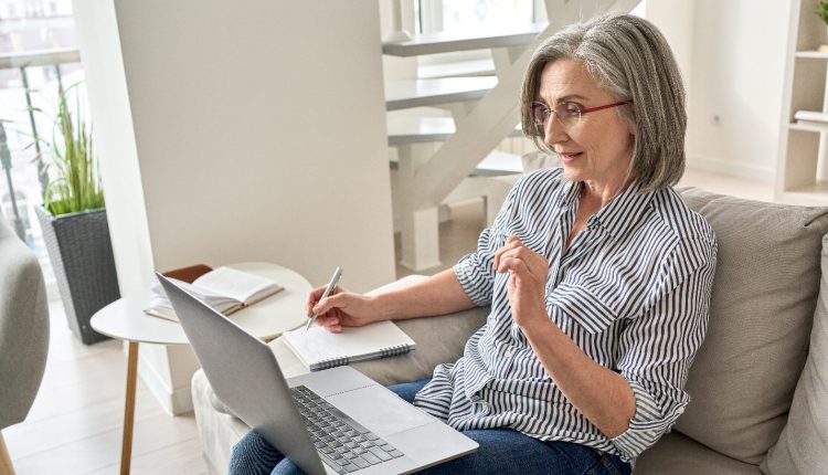 Senior woman on an online course with her laptop sitting on the couch