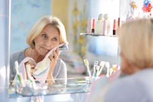 Senior woman drying her clean face in front of the bathroom mirror