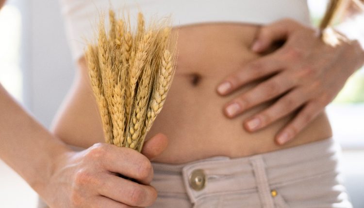 View of a woman's waist while she's holding a bunch of wheat for a gluten-free diet