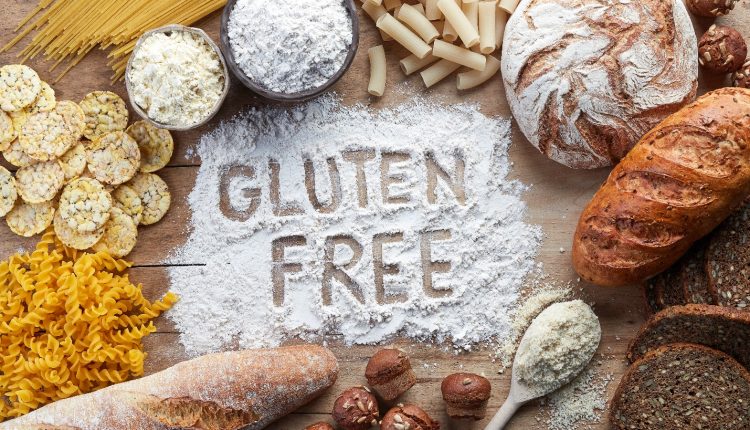 The words GLUTEN FREE written on a background of flour while surrounded by types of bread for a gluten-free diet