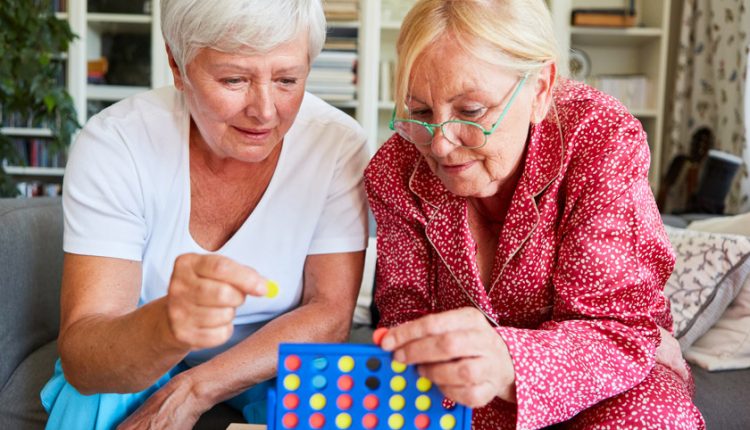 Two senior woman playing a brain game, games to play with dementia patients, games to play with the elderly with dementia
