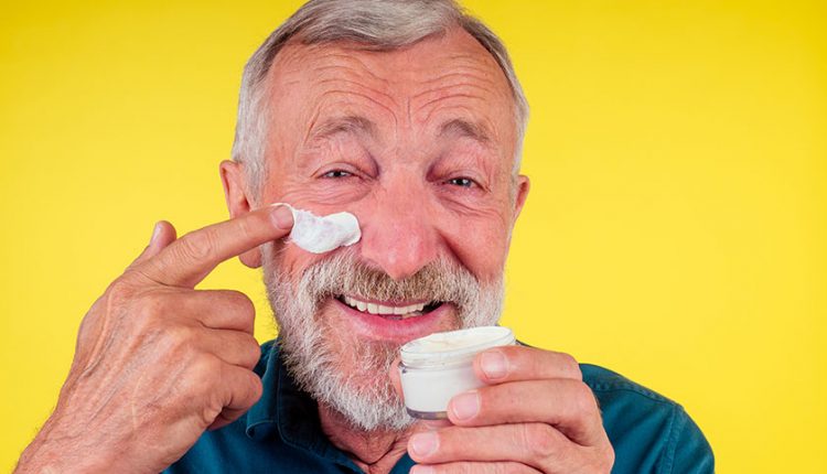 A senior man applying sunscreen on his face 