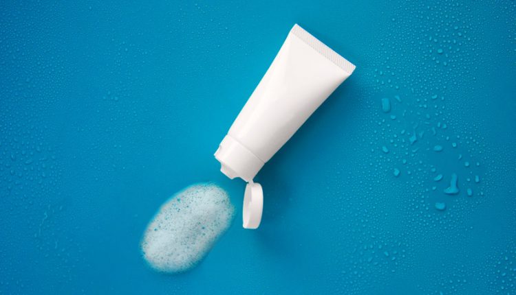 A white tube of face wash against a blue background