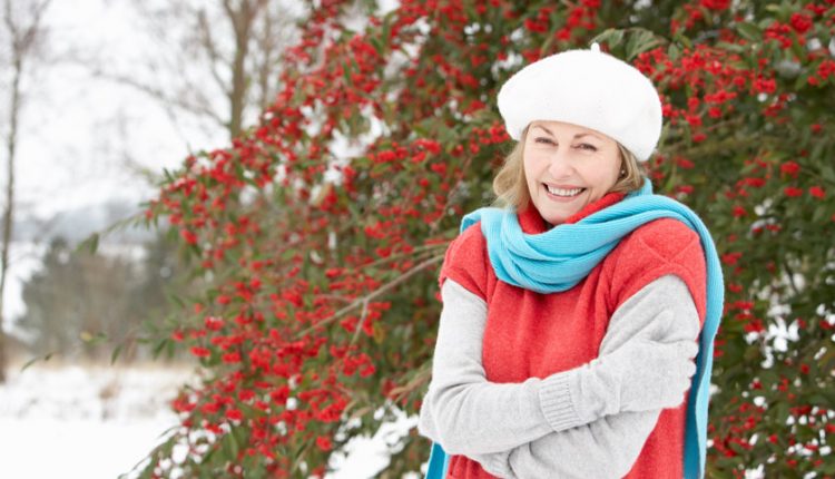 Happy senior woman standing outside in a snowy landscape