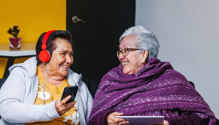Two senior women listening to music playlists and smiling at each other