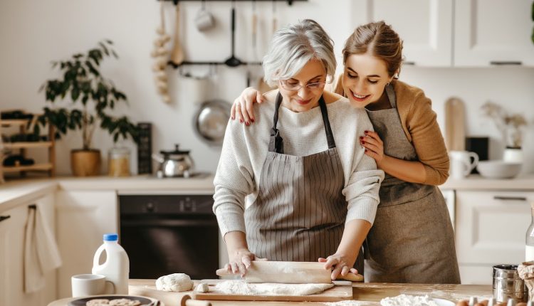 Young daughter and senior mother happily baking in the kitchen 