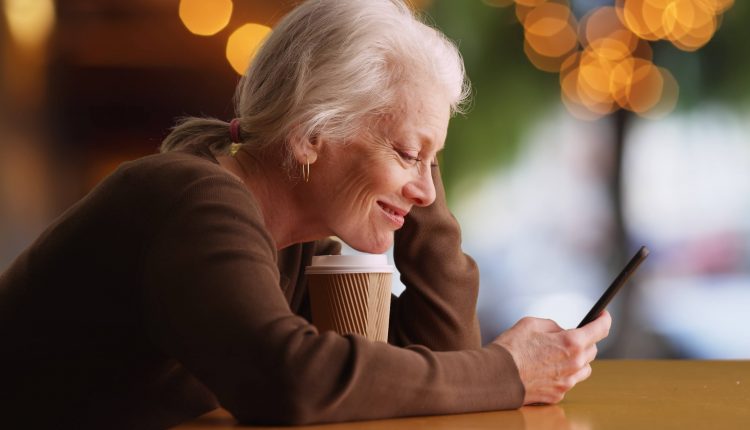 A senior woman is looking at her iPhone and smiling